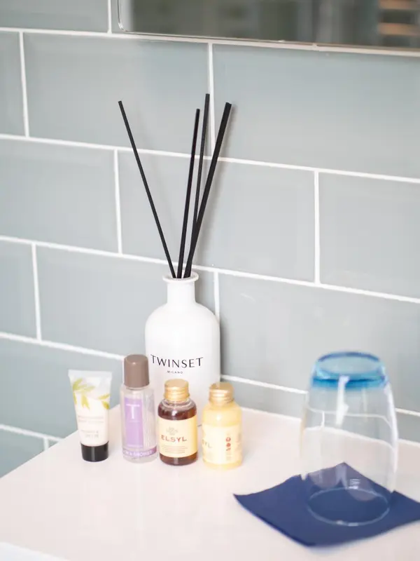 Des produits de toilette sont posés sur un comptoir blanc devant un mur carrelé.