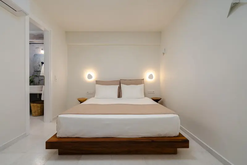 Une chambre lumineuse avec un grand lit et des luminaires muraux.