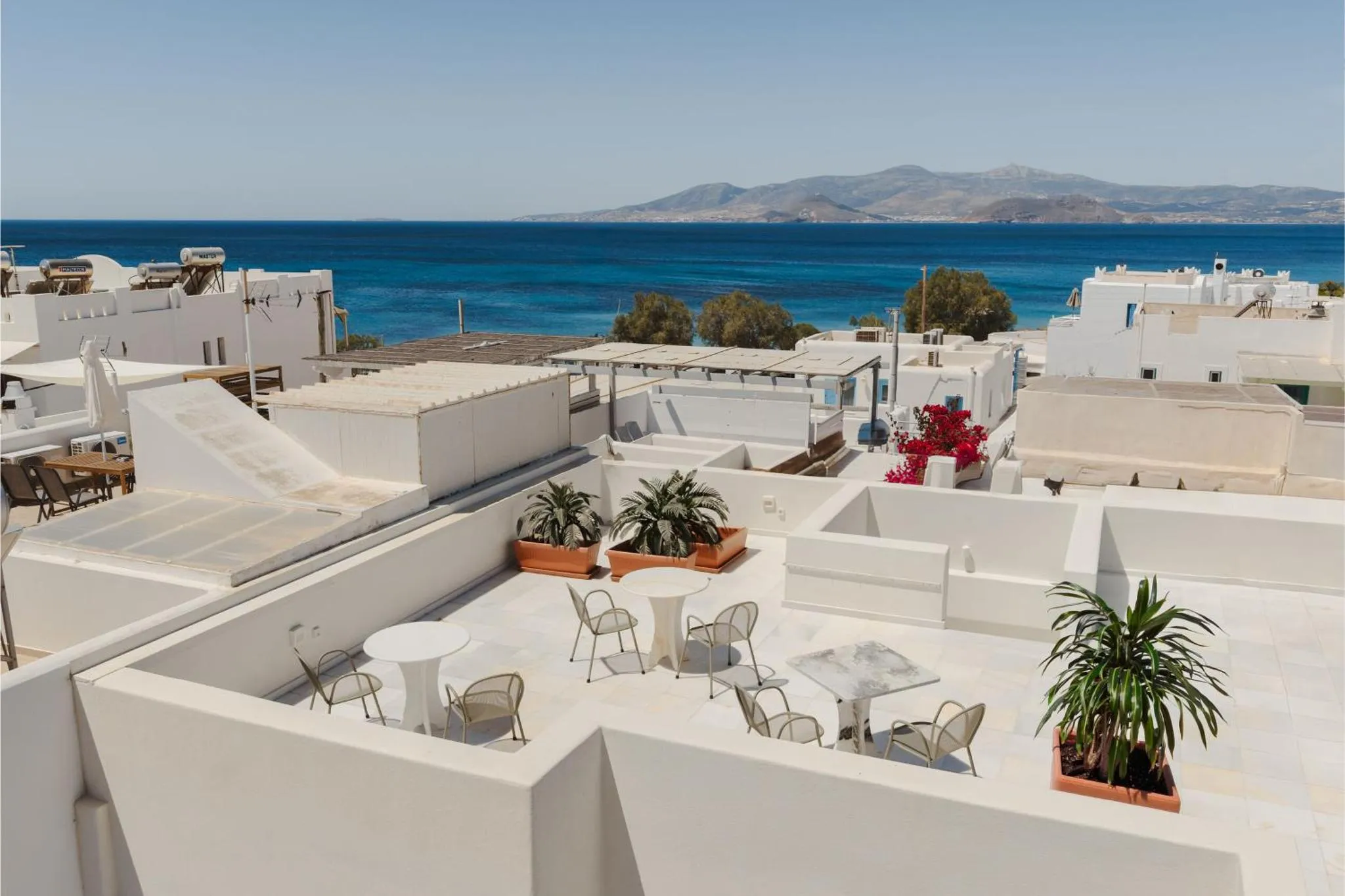 Terrasse aménagée avec tables et chaises offrant une vue sur la mer et l'horizon.