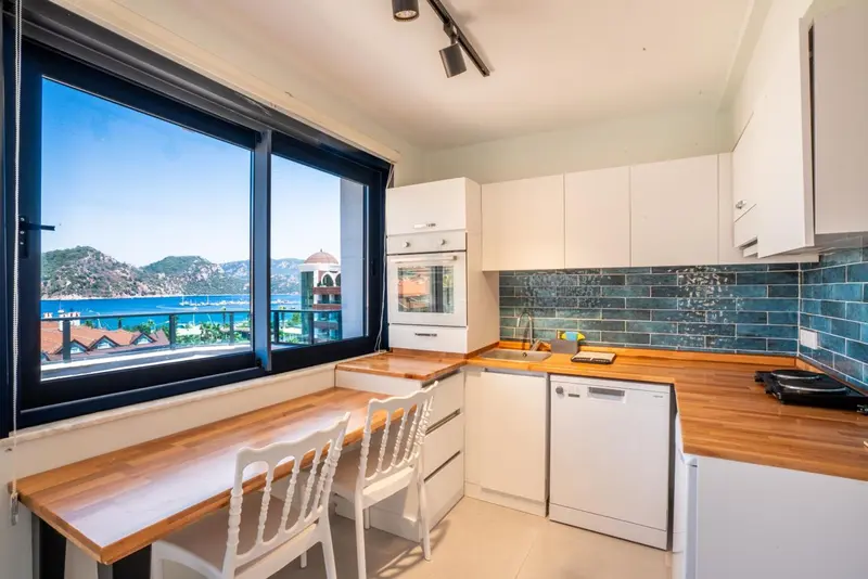 Cuisine lumineuse avec plan de travail en bois et vue sur la mer.