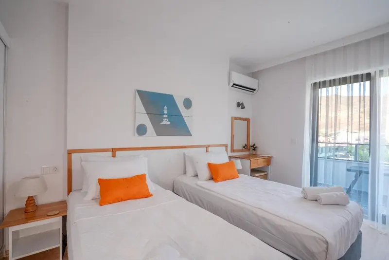 Une chambre lumineuse avec deux lits simples et un accès à un balcon.