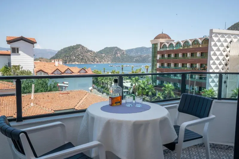 Une table ronde avec des verres et une bouteille sur un balcon ensoleillé.