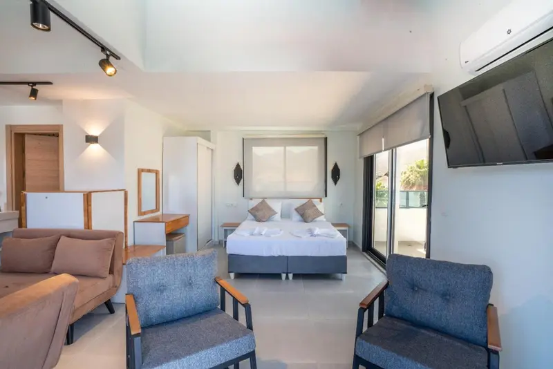 Une chambre lumineuse avec un canapé, des fauteuils et un lit fait.