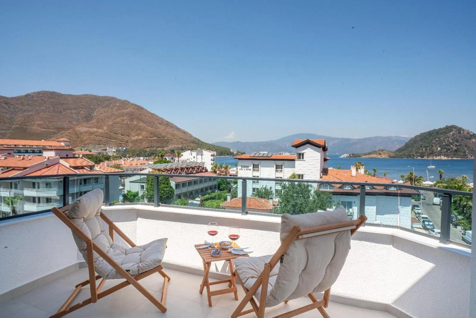 Deux fauteuils de jardin invitent à la détente sur une terrasse avec vue sur la mer et les collines.