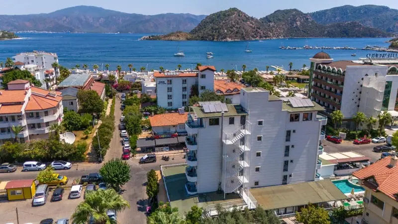 Vue aérienne d'un complexe hôtelier blanc et de bâtiments environnants au bord de la mer.
