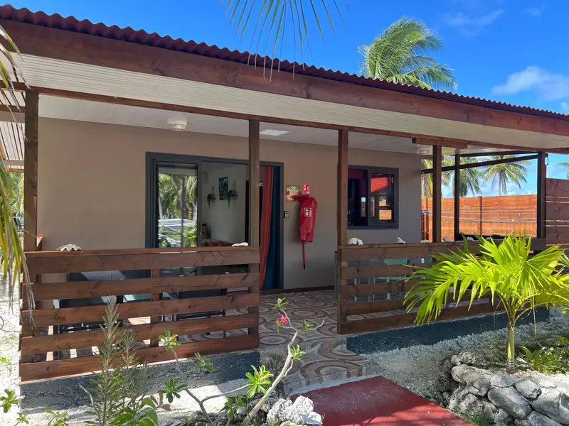 Façade d'un bâtiment avec une terrasse ombragée et une végétation tropicale.