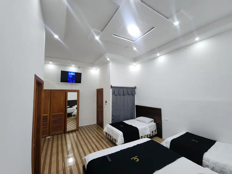 Une chambre lumineuse avec deux lits simples et un téléviseur mural.