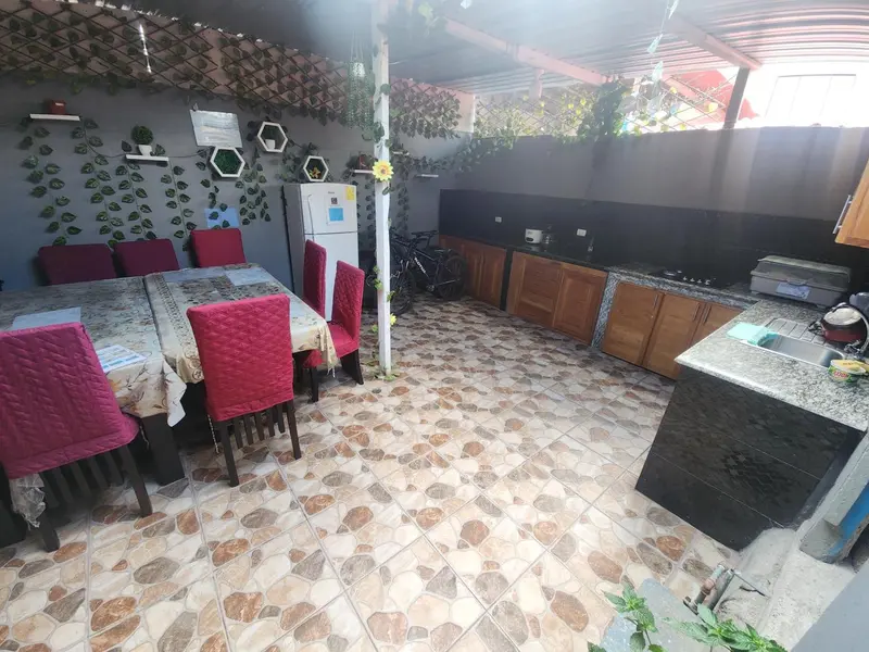Une salle à manger extérieure avec des tables et des chaises rouges, et une cuisine équipée.