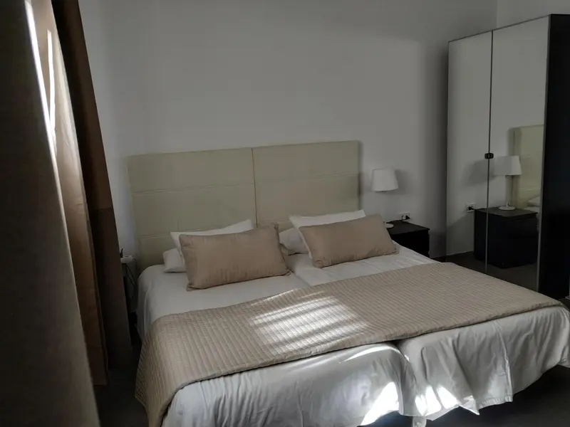 Une chambre lumineuse avec un grand lit et des tables de chevet.