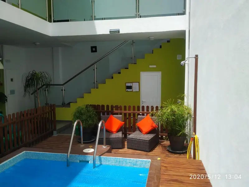 Espace piscine avec mobilier de jardin et escalier menant à un palier.