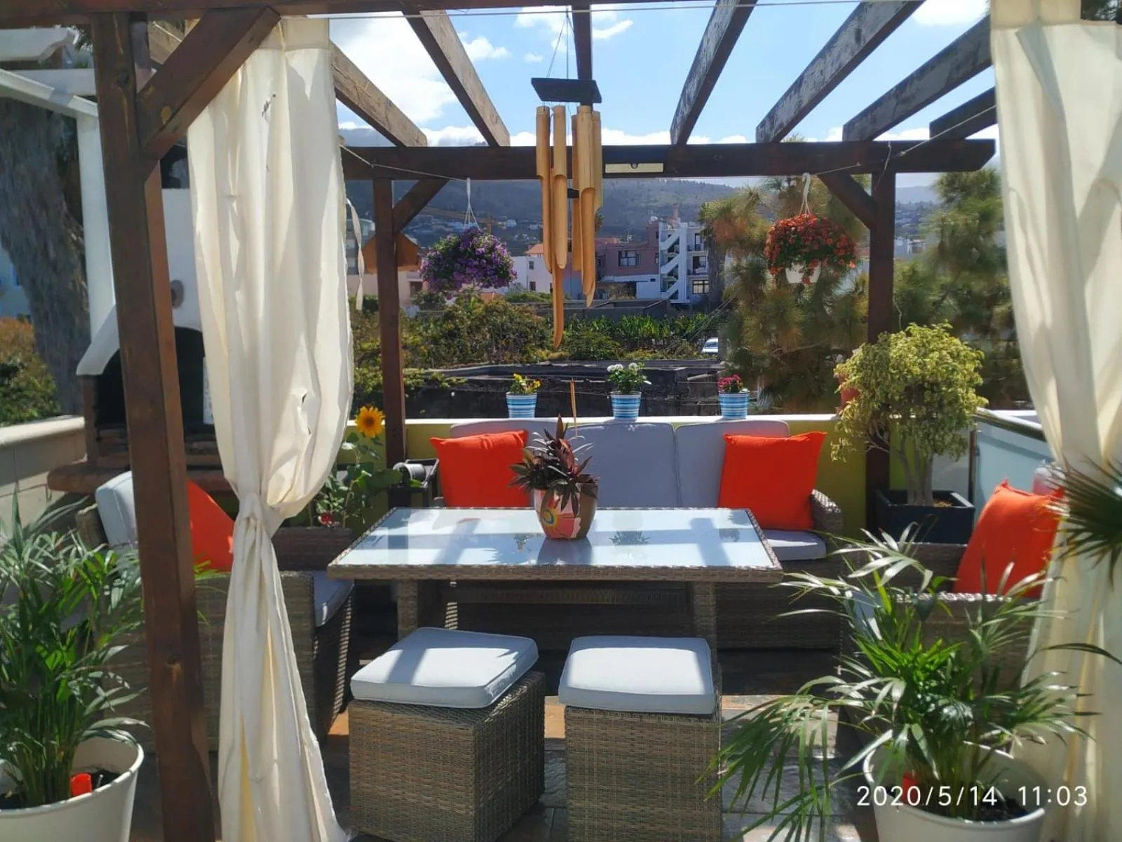 Espace de détente extérieur avec mobilier et plantes fleuries offrant une vue sur la mer.