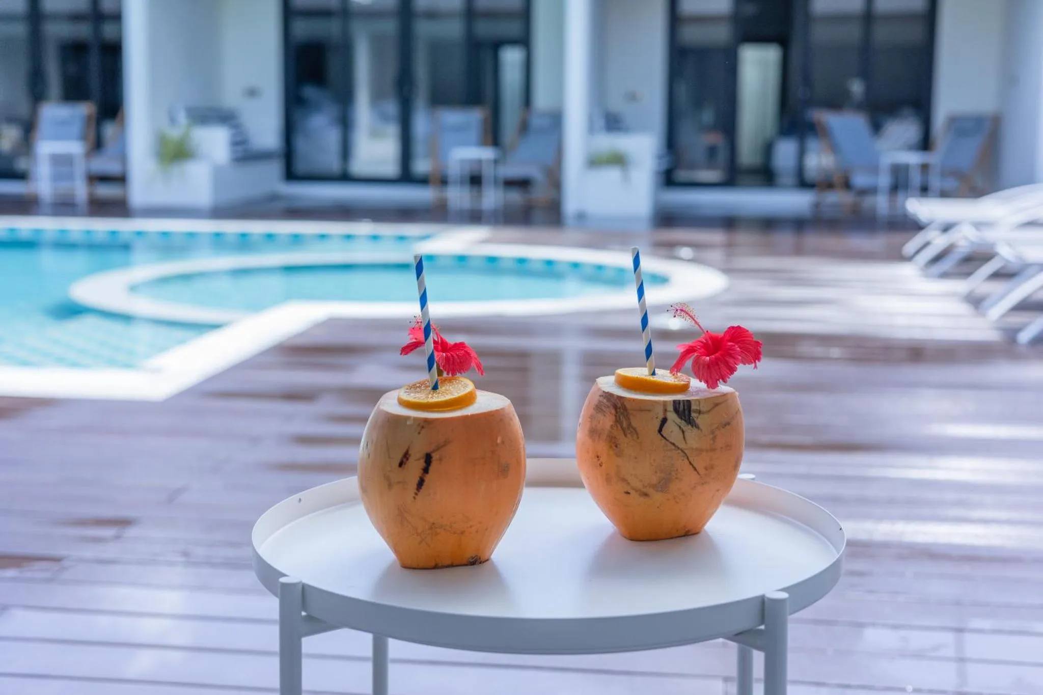 Deux cocktails exotiques servis sur une table basse au bord d'une piscine.