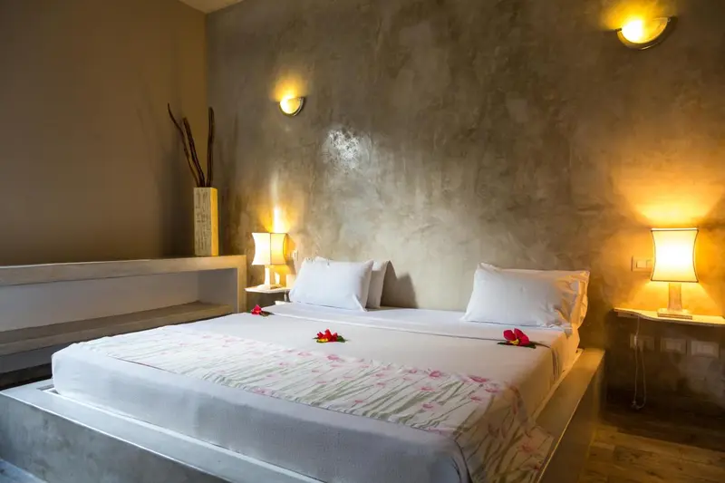 Une chambre lumineuse avec un grand lit recouvert d'une courtepointe.
