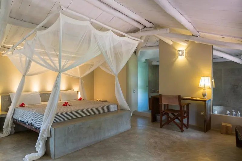 Une chambre lumineuse avec un lit à baldaquin et un bureau en bois.