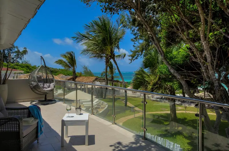Terrasse aménagée avec mobilier d'extérieur et vue sur la végétation tropicale et la mer.