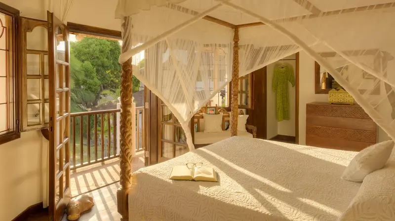 Une chambre lumineuse avec un lit à baldaquin donnant sur une terrasse.
