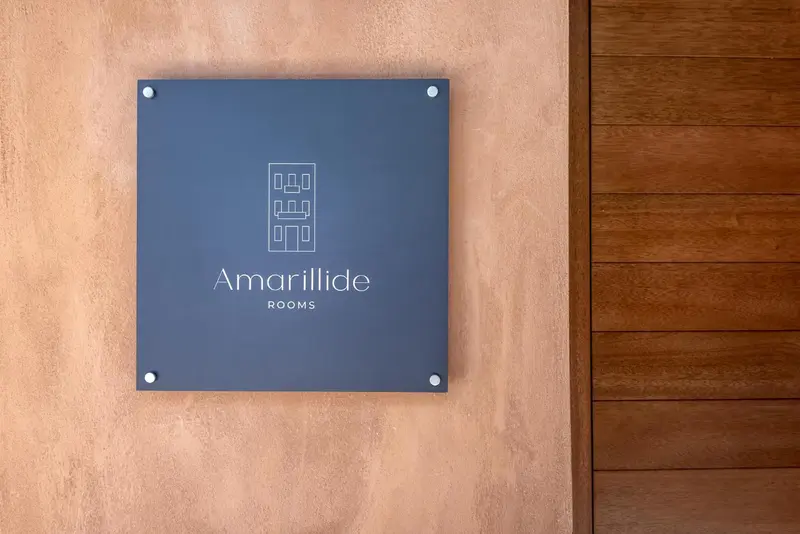 Plaque signalétique avec le nom de l'établissement et la mention 'rooms' sur un mur.