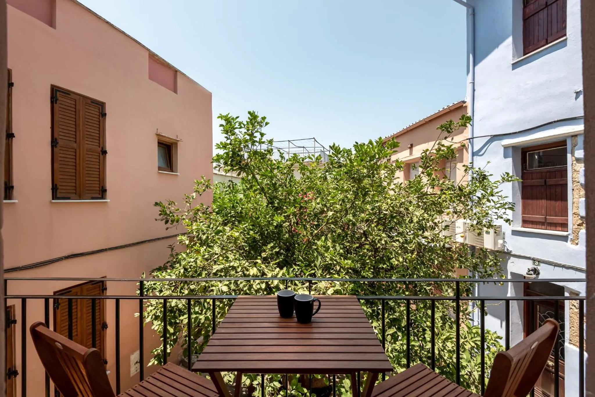 Une table et des chaises en bois se trouvent sur un balcon ensoleillé.
