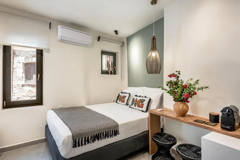 Une chambre lumineuse avec un lit recouvert d'une couverture à motifs et une décoration florale.