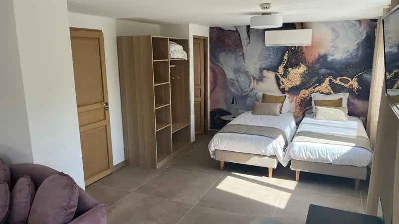 Une chambre lumineuse avec deux lits simples et un grand mur décoratif.