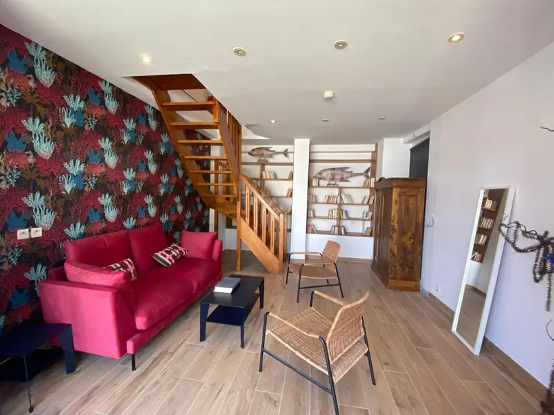 Un salon coloré avec un canapé rouge et un escalier en bois.