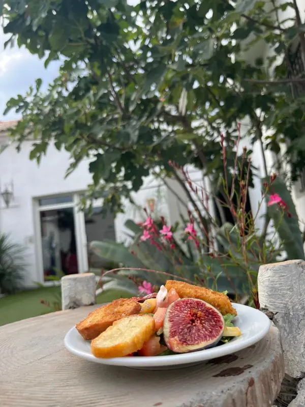 Assiette de fruits et de pâtisseries sur une table en bois devant une végétation luxuriante.