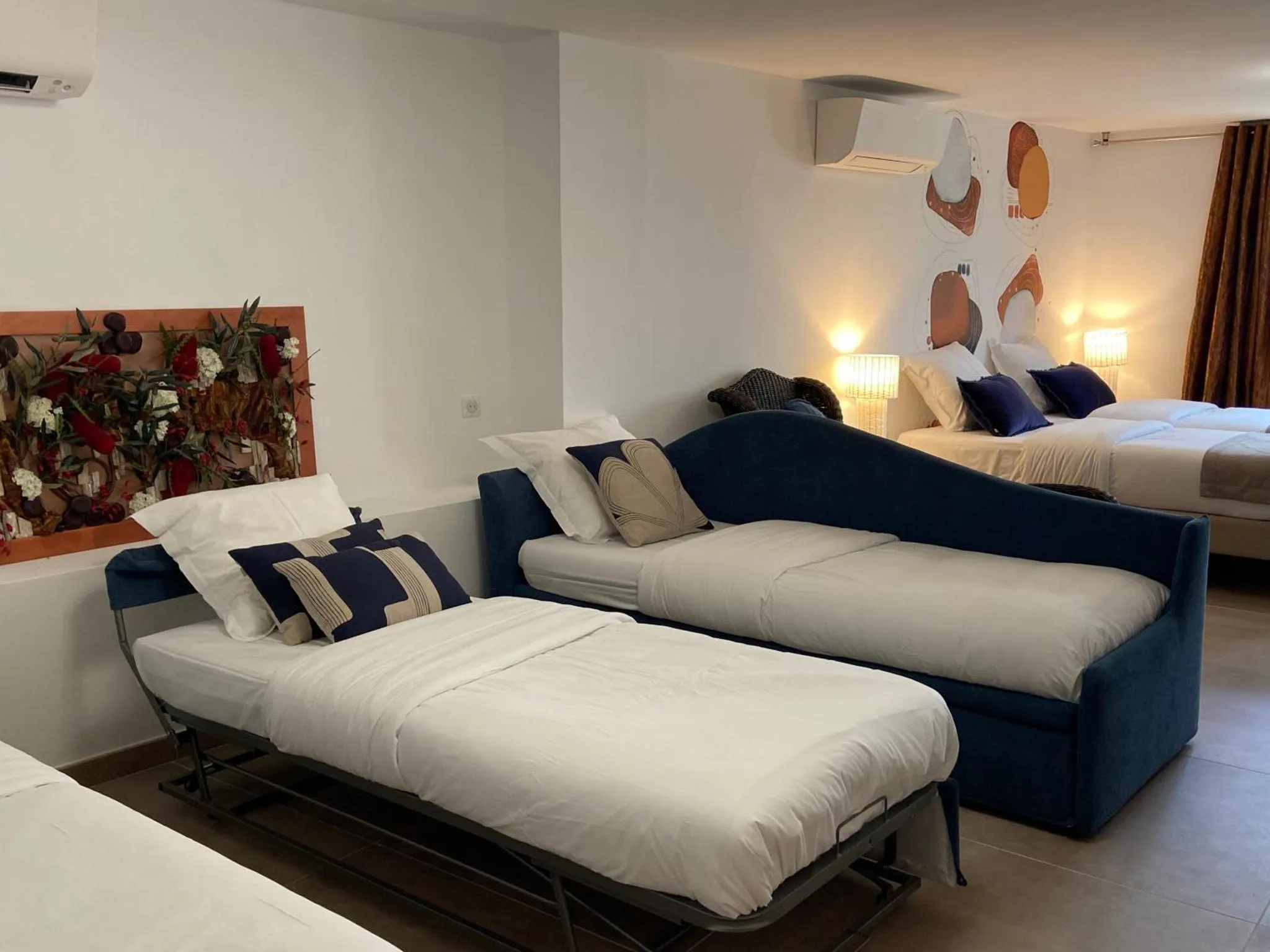 Espace de repos avec canapé bleu et lits blancs décorés de coussins.