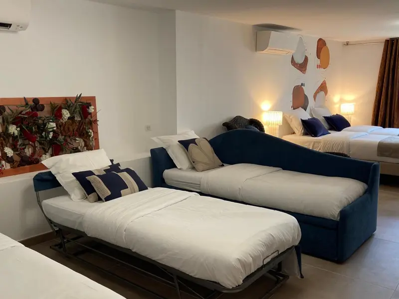 Espace de repos avec canapé bleu et lits blancs décorés de coussins.
