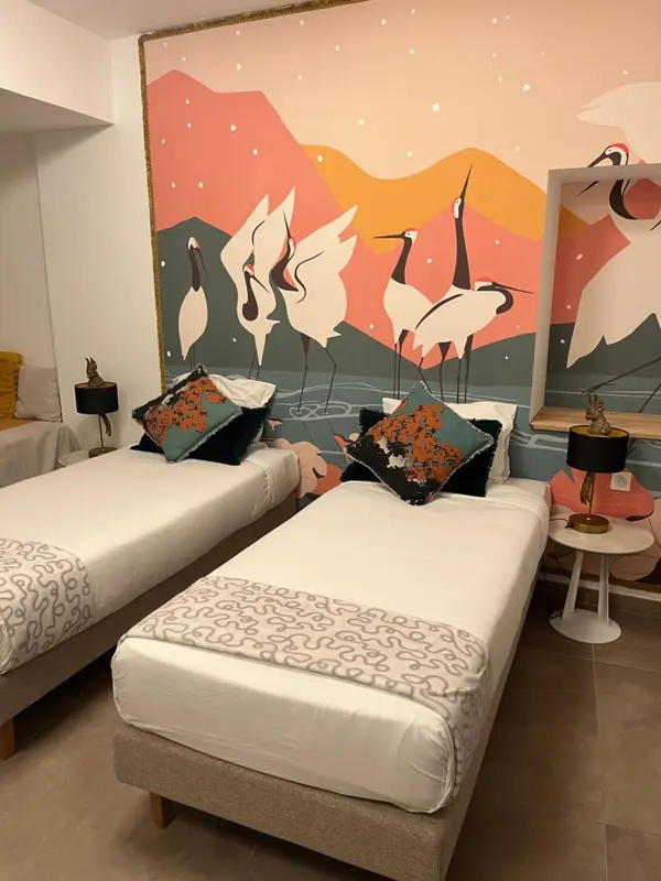 Deux lits simples décorés de coussins colorés dans une chambre d'hôtel.