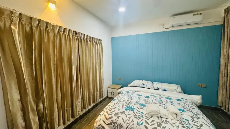 Une chambre lumineuse avec un lit recouvert d'une couette à motifs et des rideaux dorés.