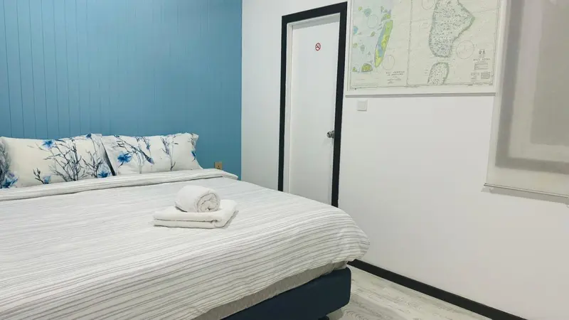 Lit préparé avec des oreillers et une serviette décorative dans une chambre lumineuse.