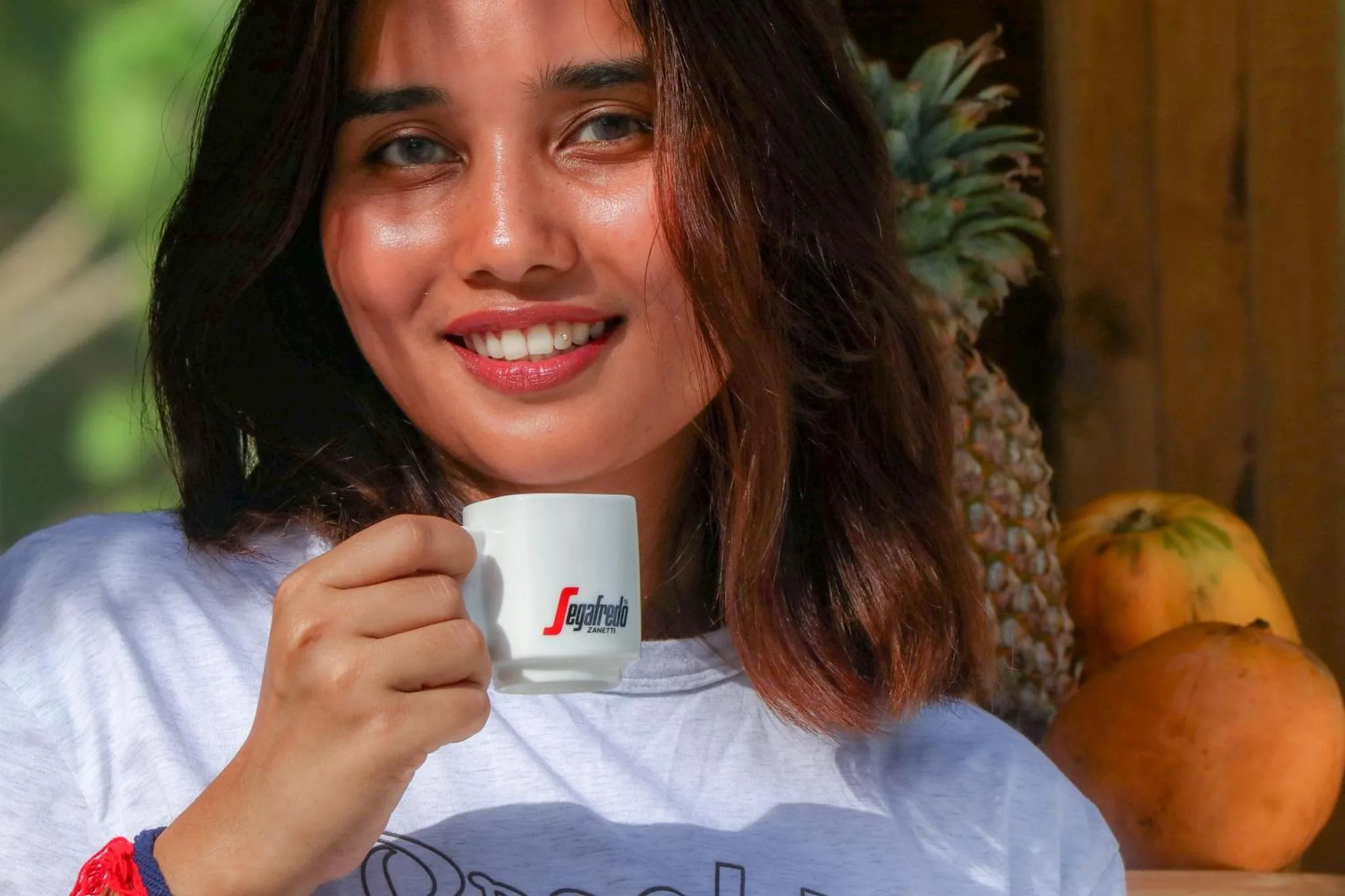 Une jeune femme souriante tient une tasse à café.