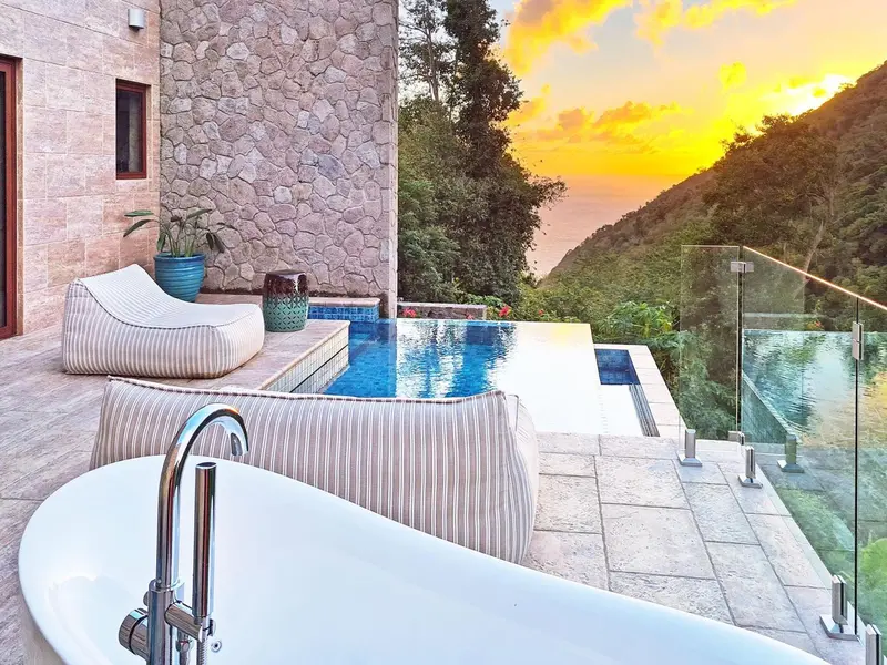 Terrasse avec jacuzzi et piscine à débordement offrant une vue sur la mer.