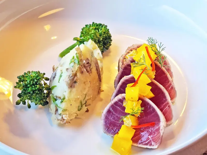 Assiette raffinée avec poisson tranché, purée et légumes verts.