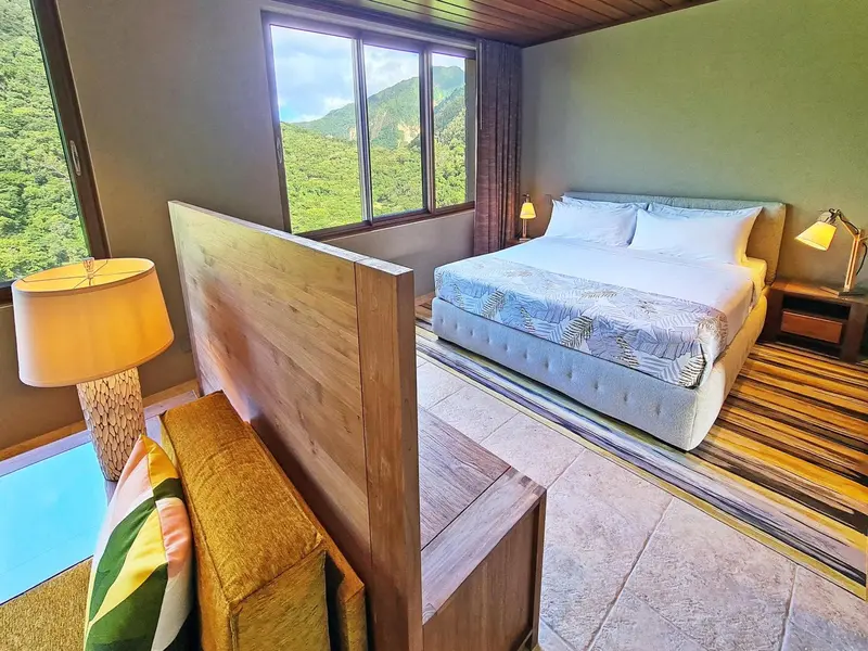 Une chambre lumineuse avec un grand lit et une vue sur une végétation luxuriante.