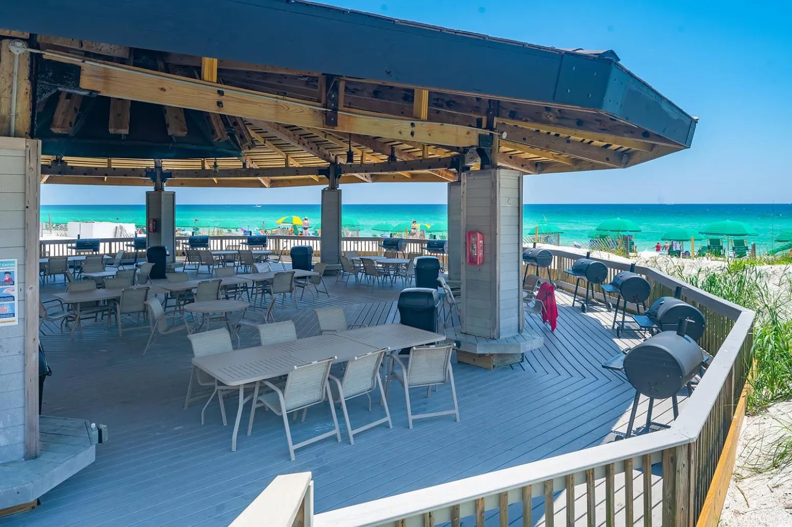 Terrasse ombragée avec tables et chaises en bord de mer.