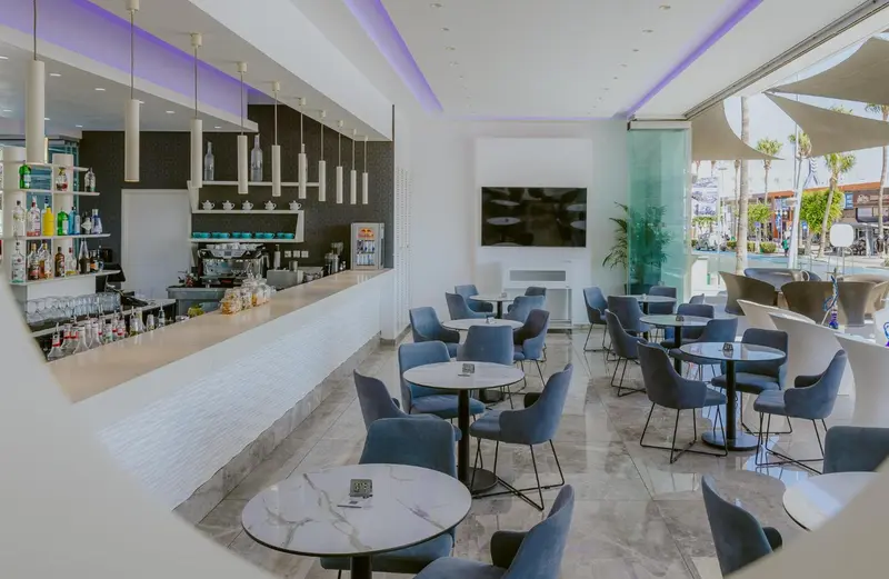 Un bar moderne avec des tabourets et des tables basses, éclairé par des suspensions.
