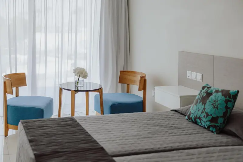 Une chambre lumineuse avec un lit et un coin salon près d'une fenêtre.
