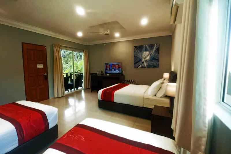 Une chambre lumineuse avec deux lits et une télévision.