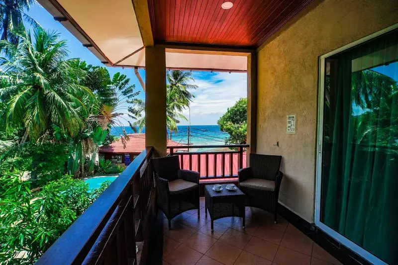 Terrasse avec mobilier d'extérieur donnant sur une végétation luxuriante et la mer.