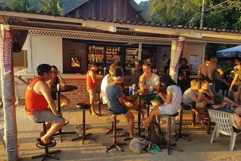 Un comptoir de bar en plein air accueille des clients assis sur des tabourets.