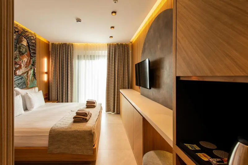 Une chambre lumineuse avec un grand lit et un téléviseur mural.
