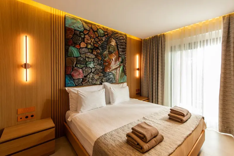 Une chambre lumineuse avec un grand lit et une décoration murale abstraite.