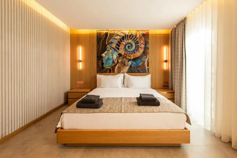 Une chambre lumineuse avec un grand lit et une décoration murale artistique.