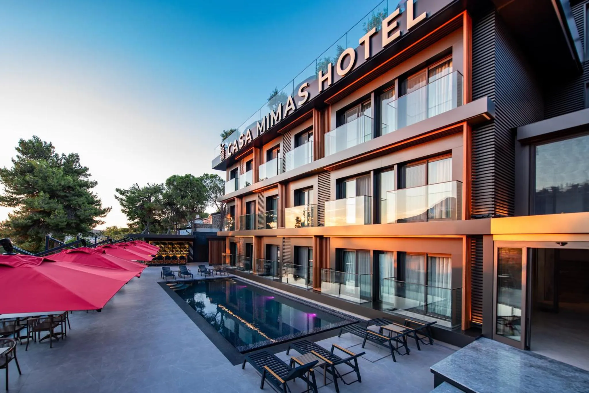 Façade d'un bâtiment moderne avec une piscine et des transats.