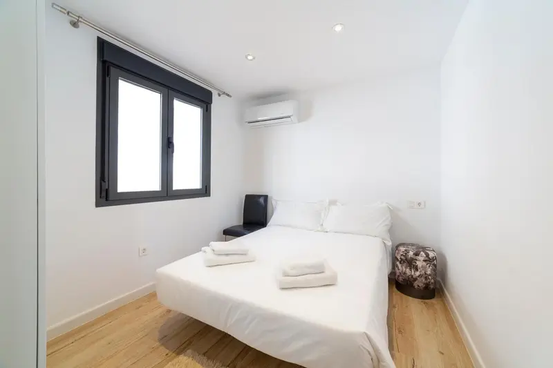 Une chambre lumineuse avec un lit fait et des serviettes.