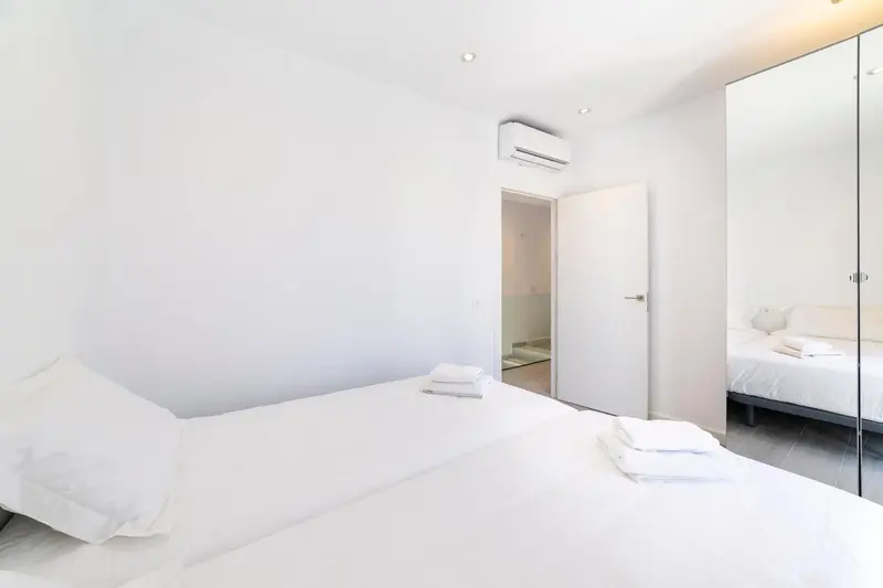 Une chambre lumineuse avec un lit fait et un grand miroir.
