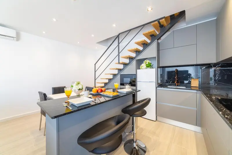 Une cuisine moderne avec un îlot central et un escalier menant à une mezzanine.