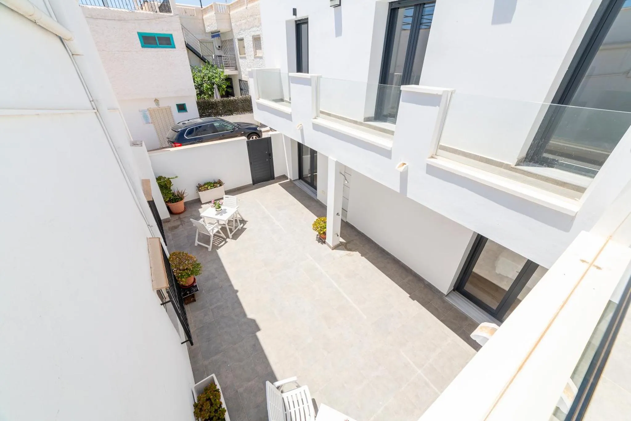 Terrasse ombragée avec mobilier de jardin et vue sur les bâtiments environnants.