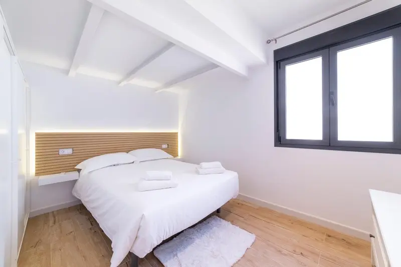 Une chambre lumineuse avec un lit double et une fenêtre.